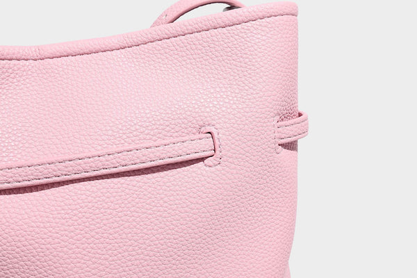Small pebbled leather-look bucket bag with front drawstring toggle hardware and long adjustable shoulder strap, detail view
