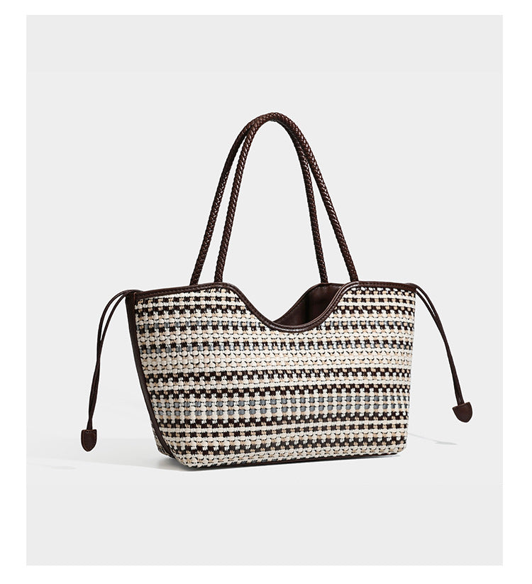 Large woven checker-pattern tote bag with dark braided shoulder straps, leather-look trim, and drawstring side ties, detail