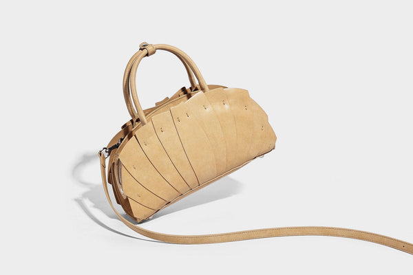 Structured dome satchel with fan-pleated leather-look exterior, dual top handles, and detachable shoulder strap, detail view