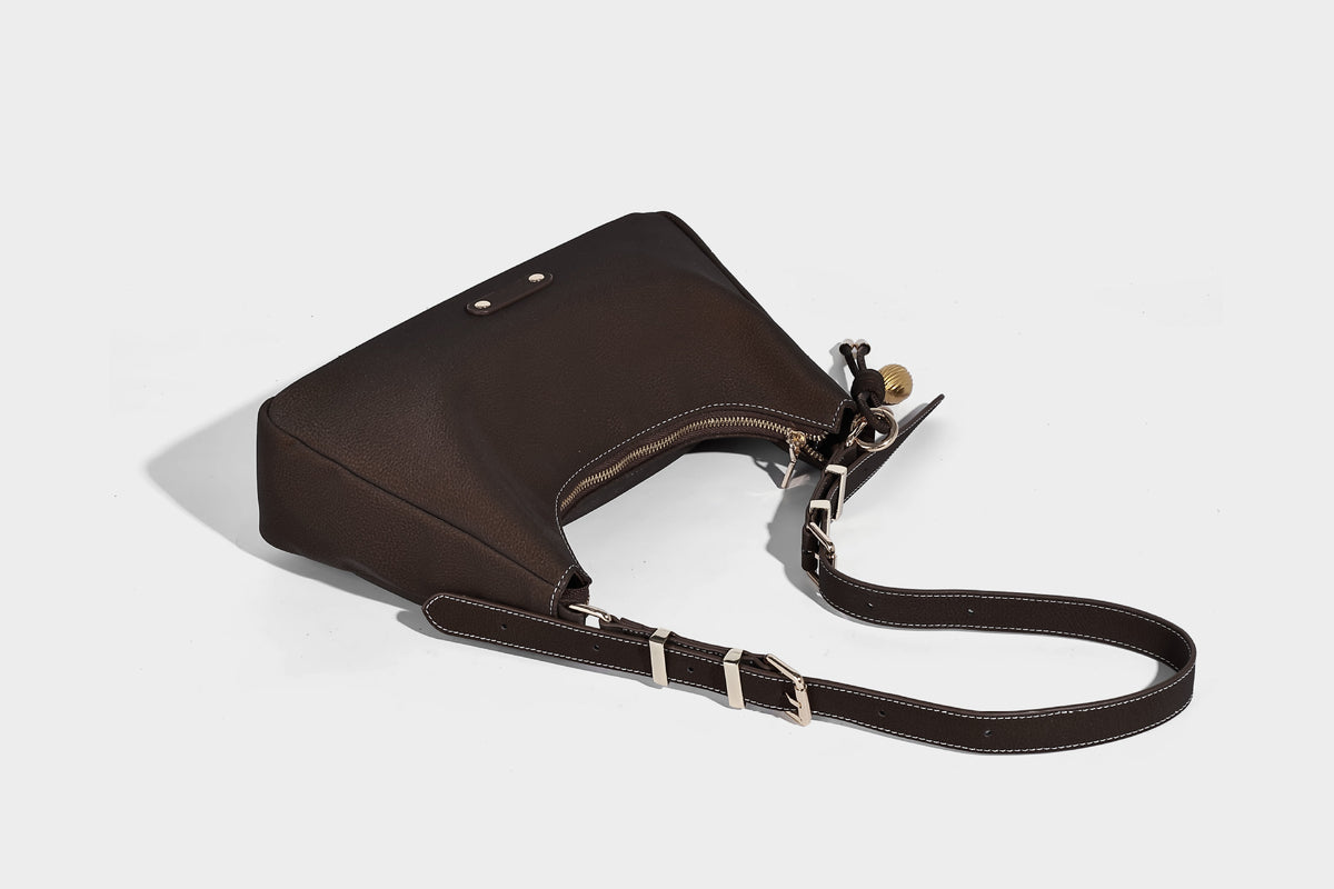 Crescent hobo shoulder bag in pebbled leather-look finish with top zipper, adjustable strap, gold-tone ring hardware, and