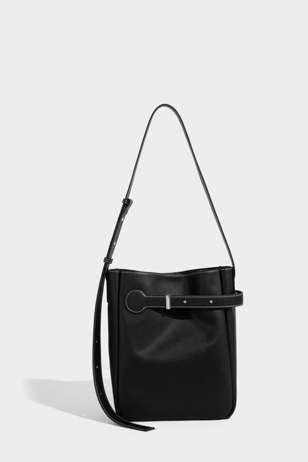 Structured dark brown leather-look bucket bag with white contrast stitching, front wraparound belt buckle strap, and long
