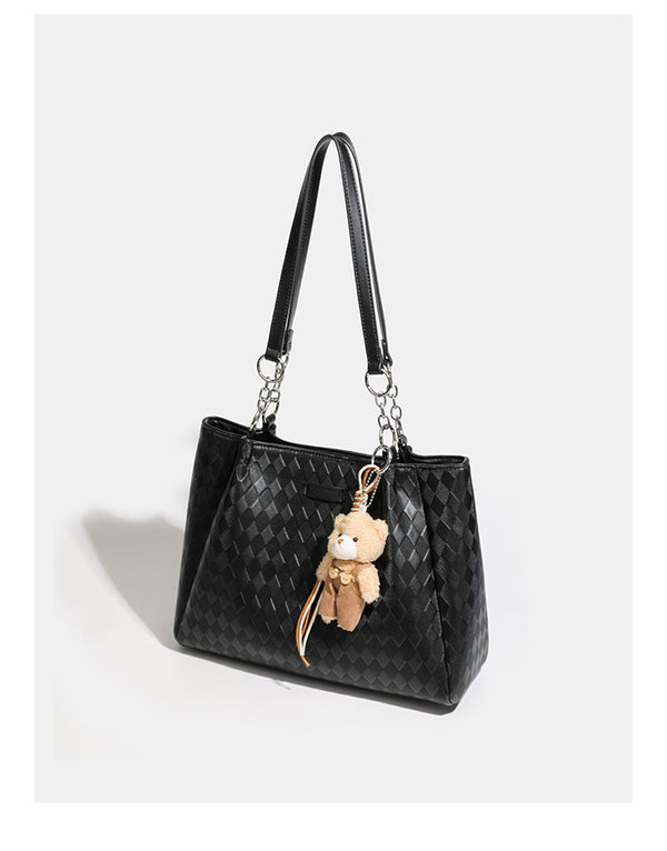 Black diamond-quilted leather-look tote bag with silver chain-ring shoulder straps and plush bear charm pendant, detail view