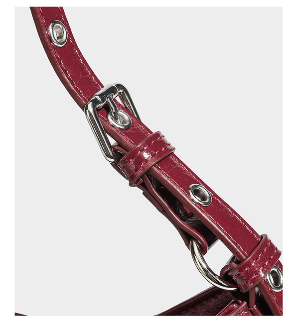 Kompakte, sichelförmige Schultertasche in glänzender bordeauxroter Lederoptik mit silberfarbenem Ösenschnallenriemen und Leopardenmuster