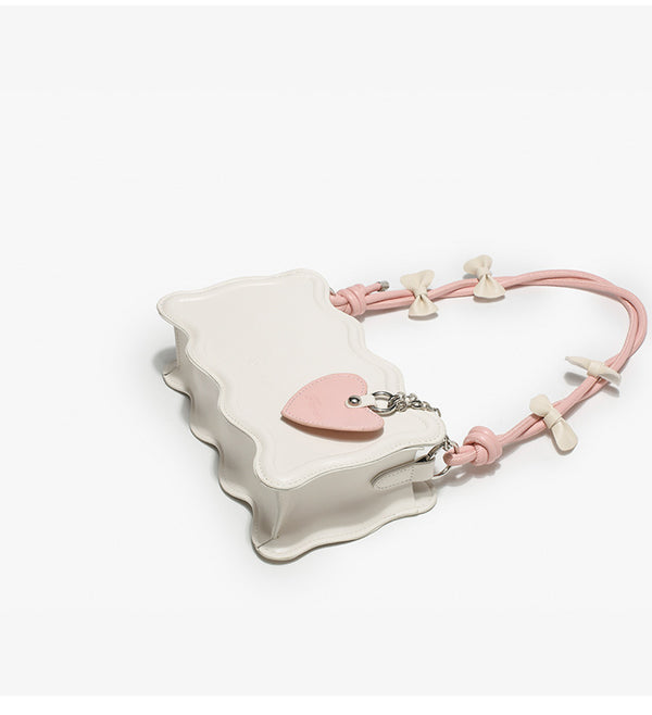 Small structured scalloped-edge shoulder bag with bow-tied pink cord strap and silver heart charm pendant, detail view 9