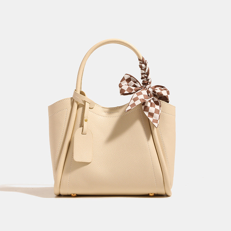 Structured pebbled tote bucket bag in apricot with braided top handle, checkered bow scarf, gold-tone hardware, and, detail