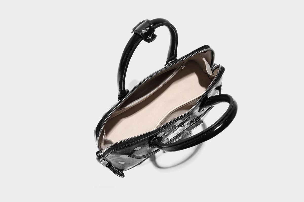 Glossy structured polka-dot satchel bag with dual top handles, silver turn-lock hardware, and detachable shoulder strap