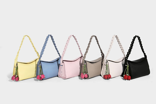Small structured pebbled-finish shoulder bag with braided top handle, detachable crossbody strap, floral tassel charm, and