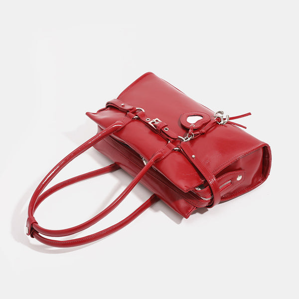 Strukturierte, glänzende trapezförmige Schultertasche mit zwei Henkeln oben, umlaufendem Riemen, silberfarbenem Verschluss und hängendem
