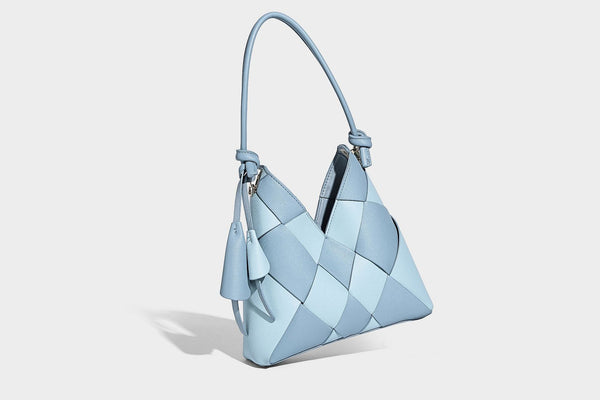Compact bucket shoulder bag with black-and-white diamond patchwork panels, knotted top handle, gold-tone hardware, and