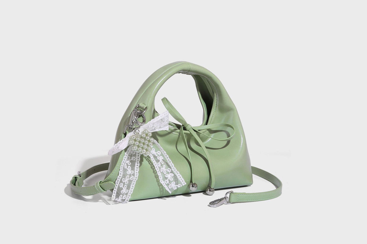 Kleine kuppelförmige Henkeltasche in glänzender Lederoptik mit Kordelzugverschluss, weißem Spitzen-Schleifenanhänger und silberfarbenen Metallbeschlägen