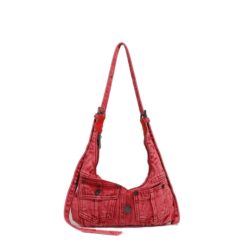 Compact washed red distressed-textile shoulder bag with front flap pockets, dark metal hardware, and long adjustable strap