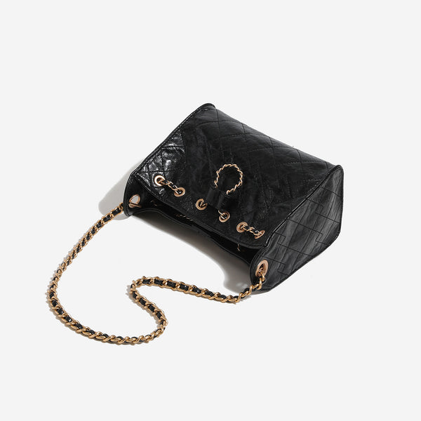 Glossy diamond-quilted drawstring bucket bag with gold-tone chain strap and eyelet hardware, detail view 4