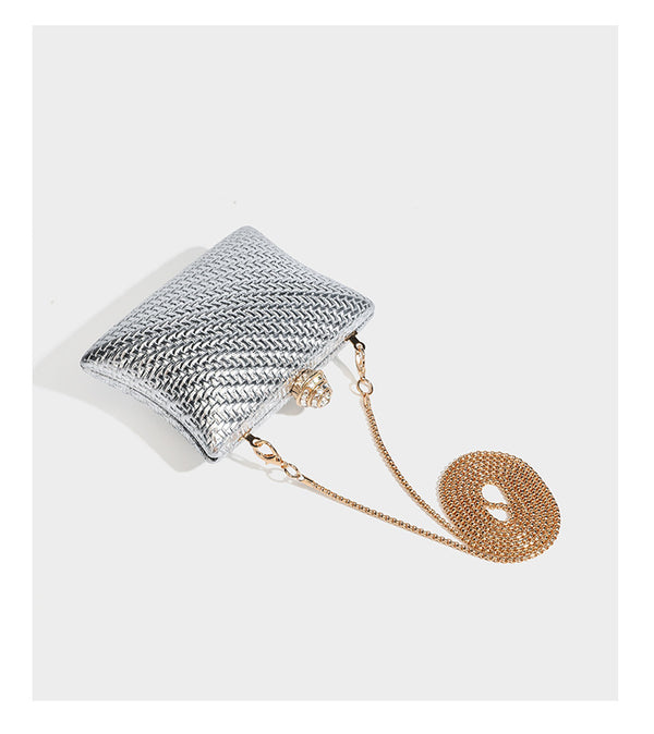 Small structured rectangular metallic woven-texture clutch bag with jeweled knob clasp and gold-tone chain strap, detail view