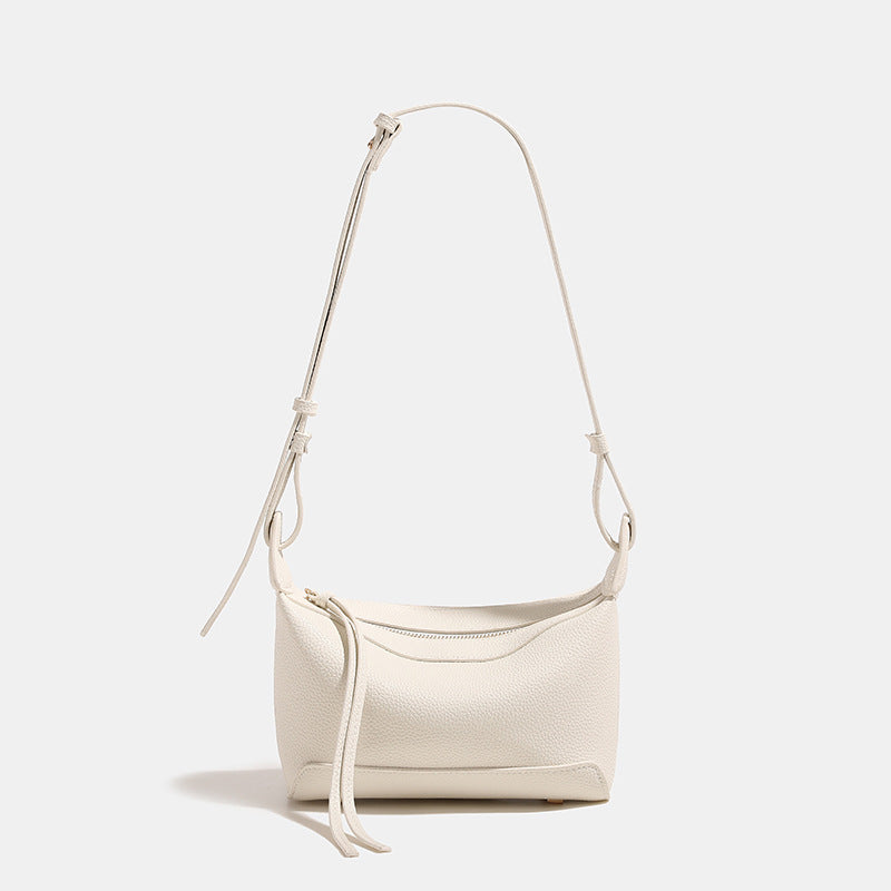 Small structured mini crossbody shoulder bag with pebbled texture, knotted adjustable strap, top zip closure, and gold-tone