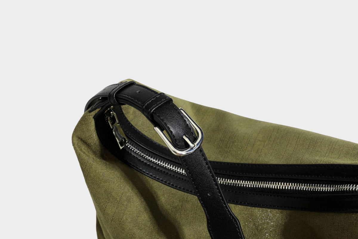 Slouchy olive green canvas hobo shoulder bag with black leather-look trim, zip-top closure, and adjustable strap, detail view