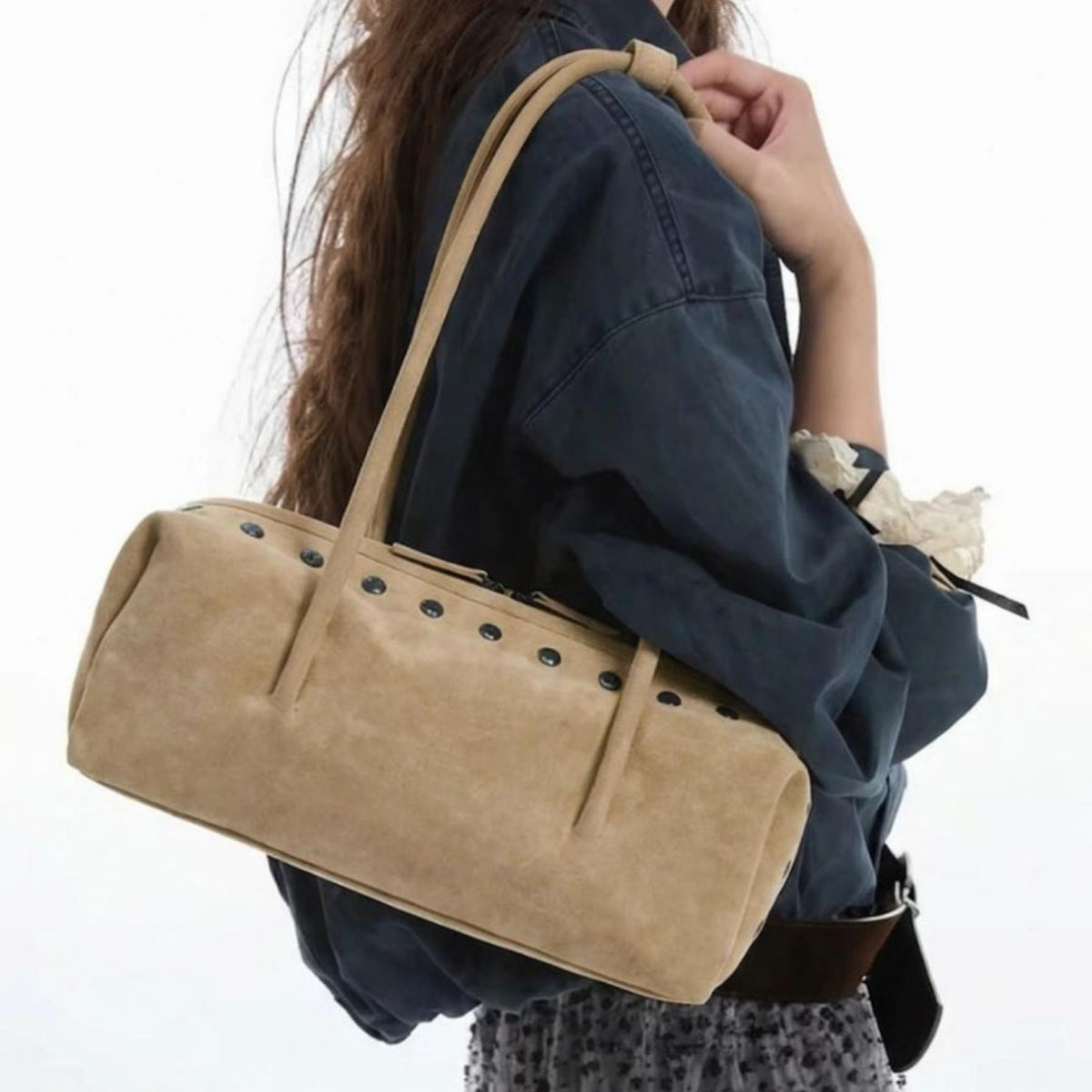 Rechteckige, tonnenförmige Schultertasche mit kuppelförmigen Nieten in Gunmetal-Optik entlang der oberen Naht, zwei flachen Riemen mit Knotendetail und mattem Finish, Detailansicht