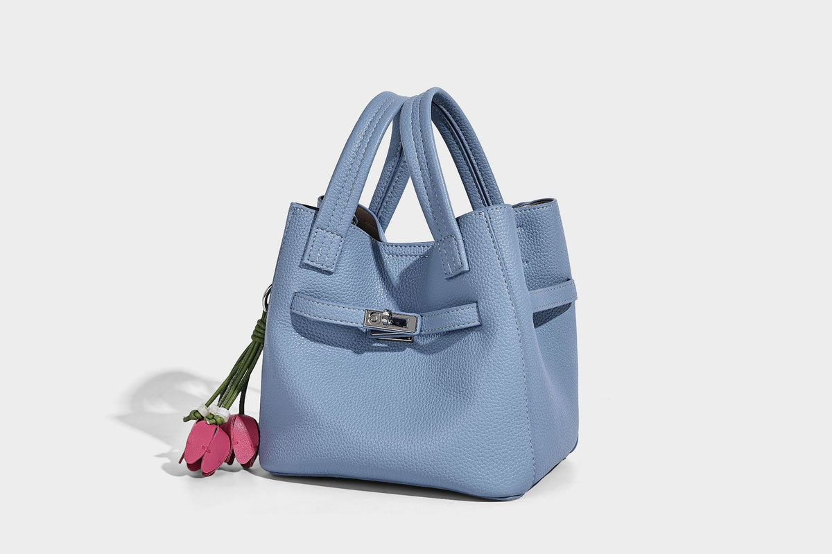 Small structured pebbled bucket tote bag with dual top handles, silver turn-lock front pocket, and detachable shoulder strap