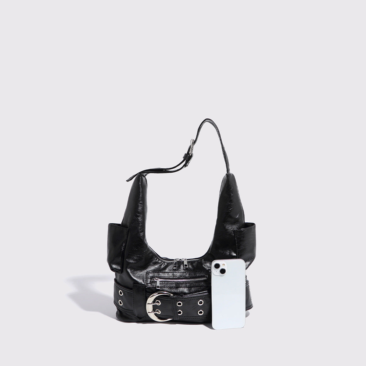 Große schwarze Hobo-Schultertasche in glänzender Lederoptik mit silberfarbener Gürtelschnalle, Ösenbesatz und vorderer Reißverschlusstasche, Detailansicht