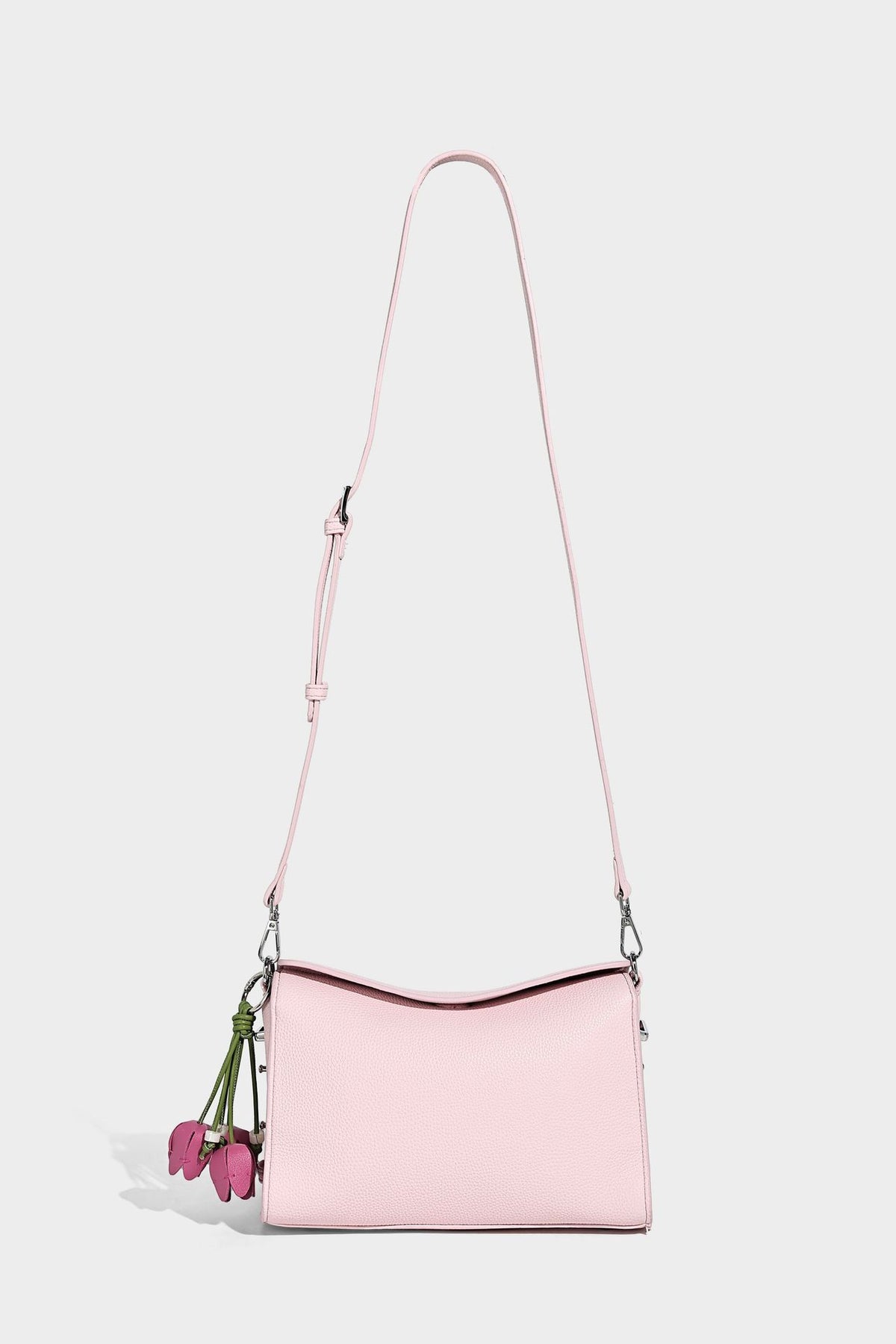 Small structured pebbled-finish shoulder bag with braided top handle, detachable crossbody strap, floral tassel charm, and