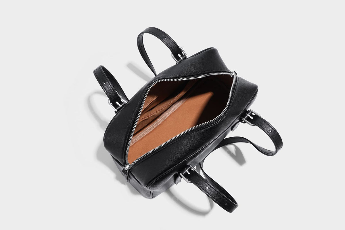 Structured dome-shaped shoulder bag with leather-look finish, top zipper closure, dual adjustable slim straps, and, detail