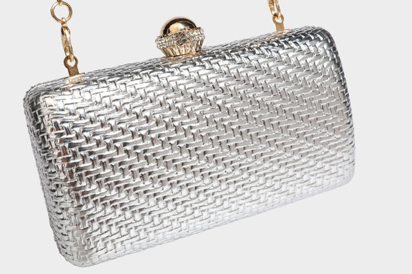 Small structured metallic woven-texture box clutch bag with jeweled kiss-lock dome clasp and slim gold chain strap, detail