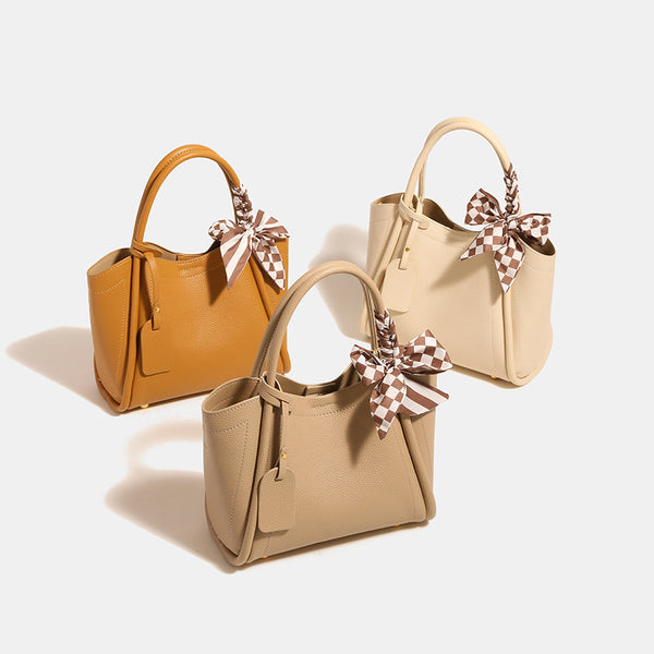 Structured pebbled tote bucket bag in apricot with braided top handle, checkered bow scarf, gold-tone hardware, and, detail