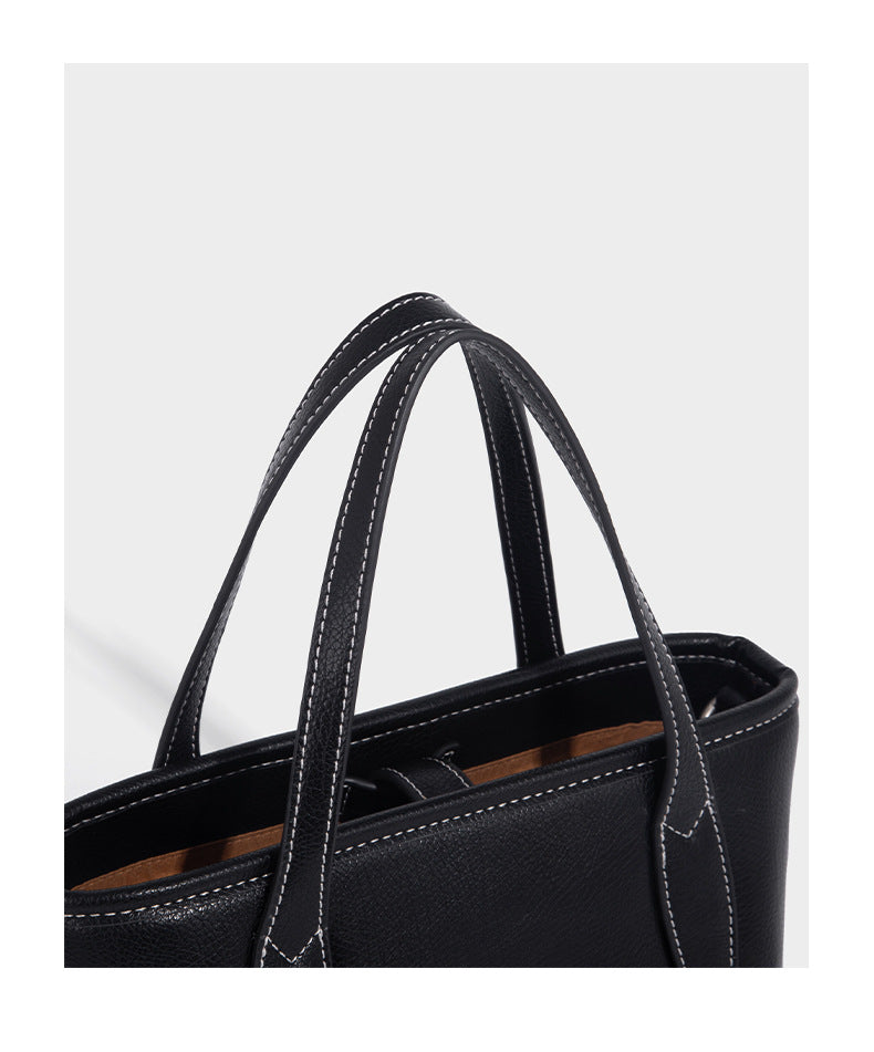 Compact structured bucket tote bag with pebbled textured finish, dual top handles, silver-tone lock hardware, and detachable