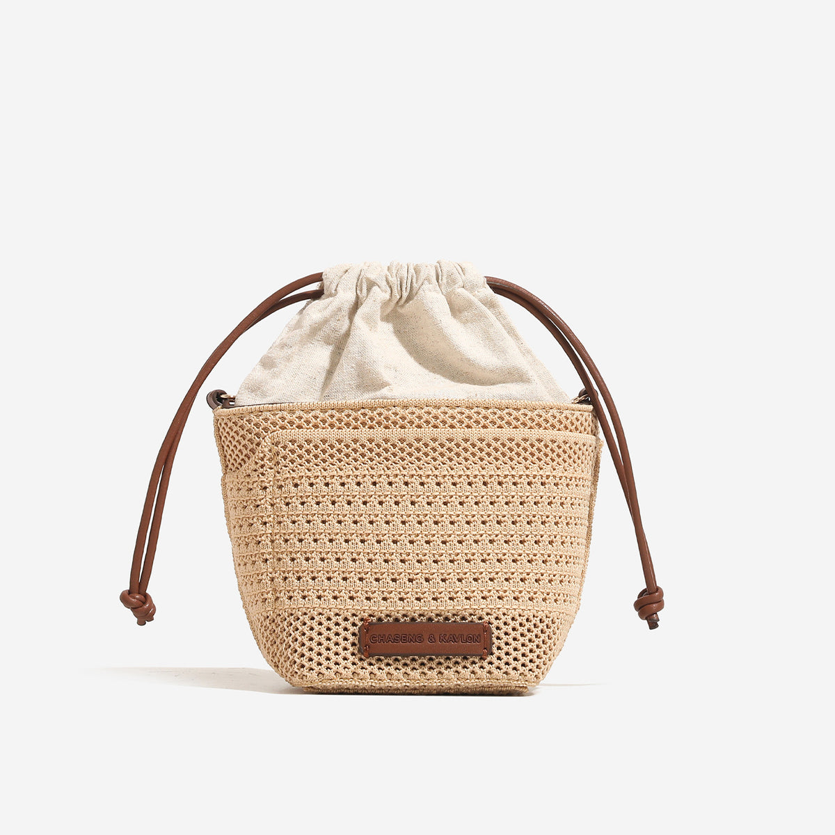Compact openwork woven bucket bag with gathered cream drawstring liner, leather-look brown trim and cords, and gold-tone
