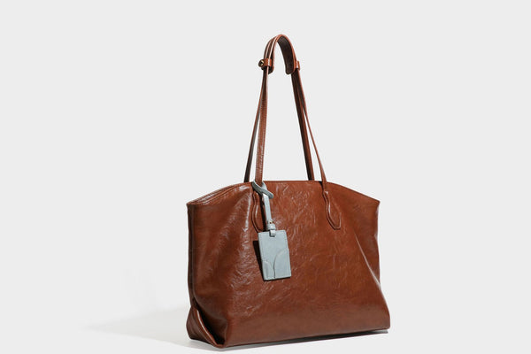 Übergroße, weich fallende Tote-Bag in dunklem Bordeauxrot mit glänzender, geknautschter Lederoptik, zwei langen Schulterriemen und Kontrast