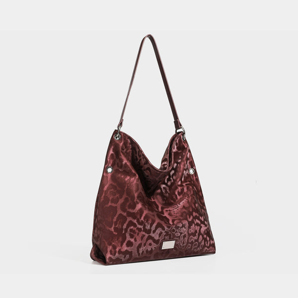 Lässig fallende Hobo-Schultertasche mit Leopardenprint, glänzender satinähnlicher Oberfläche, silberfarbenen Ringbeschlägen und schmalem Schulterriemen