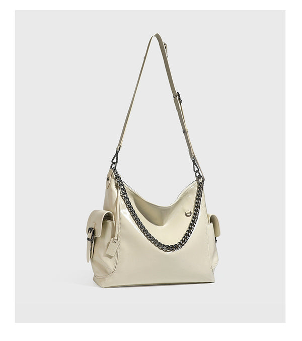 Slouchy hobo shoulder bag with glossy leather-look finish, silver-tone chain drape across front, side buckle pockets, and