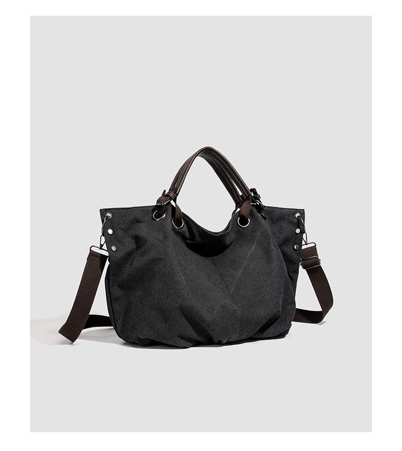 Slouchy matte canvas tote bag with dark dual top handles, metal grommet hardware, and detachable long shoulder strap, detail