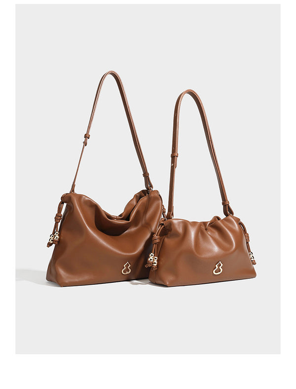 Slouchy ruched drawstring shoulder bag in smooth leather-look finish with gold-tone emblem and slim adjustable strap, detail
