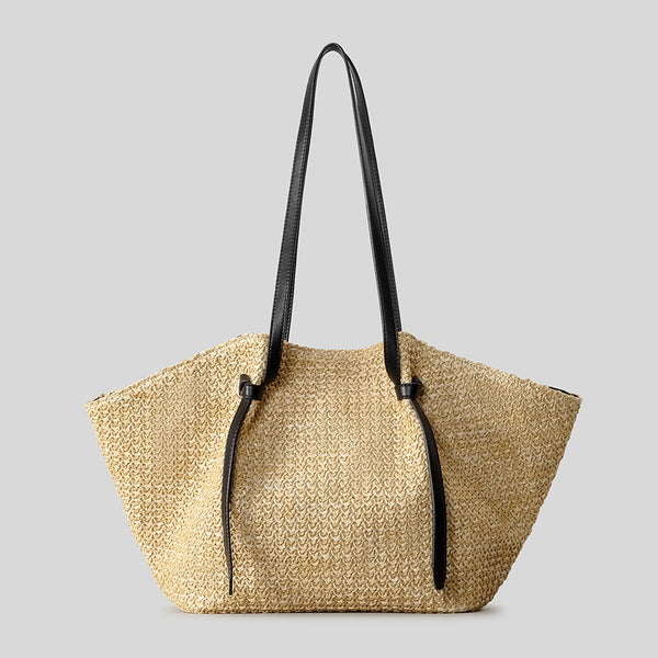 Große Tote-Bag aus geflochtenem Stroh mit Schulterriemen aus schwarzem Lederimitat und geknoteten Riemendetails, trapezförmiger Korpus in Natur-Tan