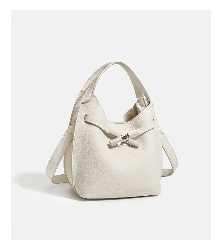 Compact pebbled leather-look shoulder bag with crossed silver-toned metal front closure, short top handle, and long, detail