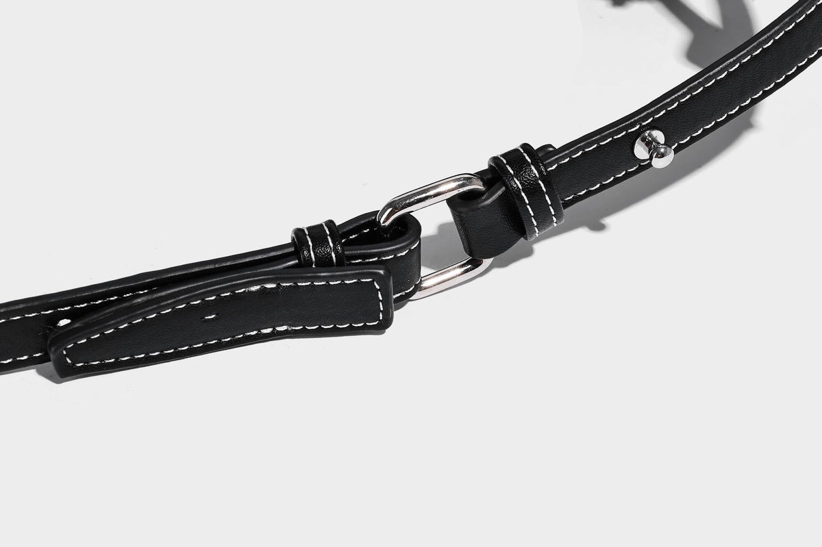 Small slouchy moto-style crossbody bag in smooth matte leather-look finish with white contrast stitching, silver-tone, detail