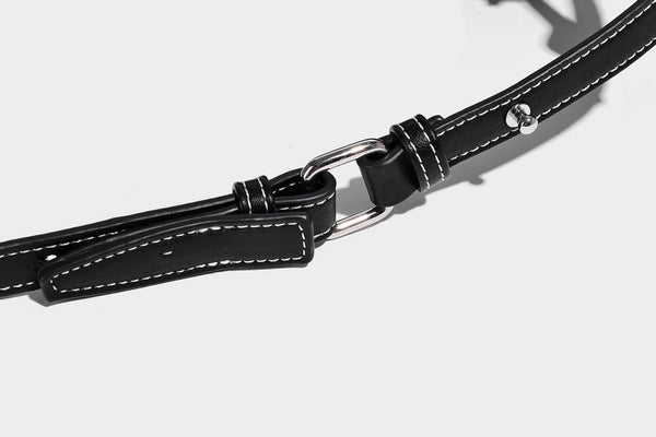 Small slouchy moto-style crossbody bag in smooth matte leather-look finish with white contrast stitching, silver-tone, detail