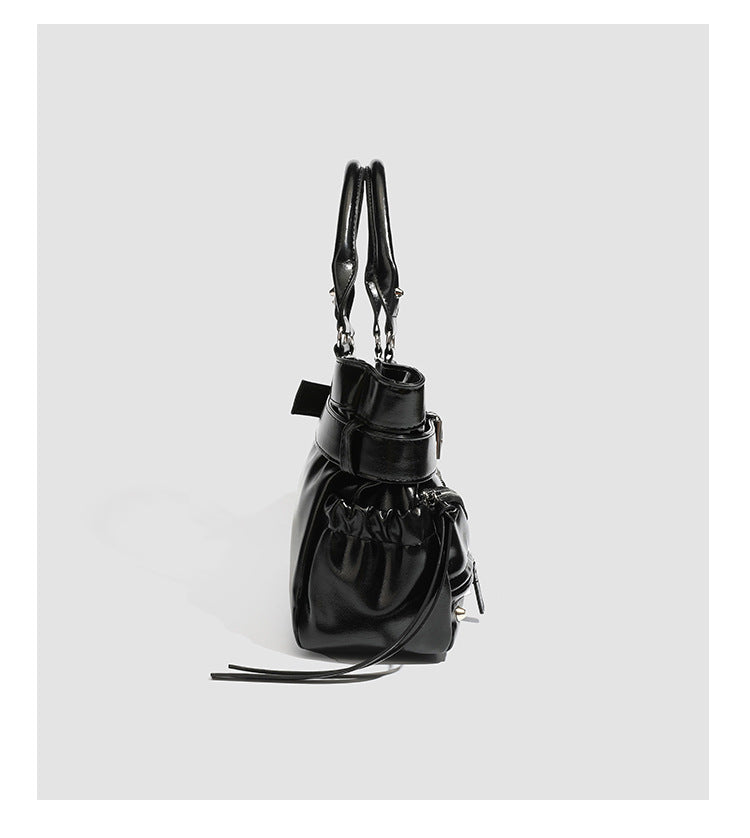 Black glossy structured tote bag with rivet and buckle detail, dual top handles, and detachable shoulder strap, detail view 9