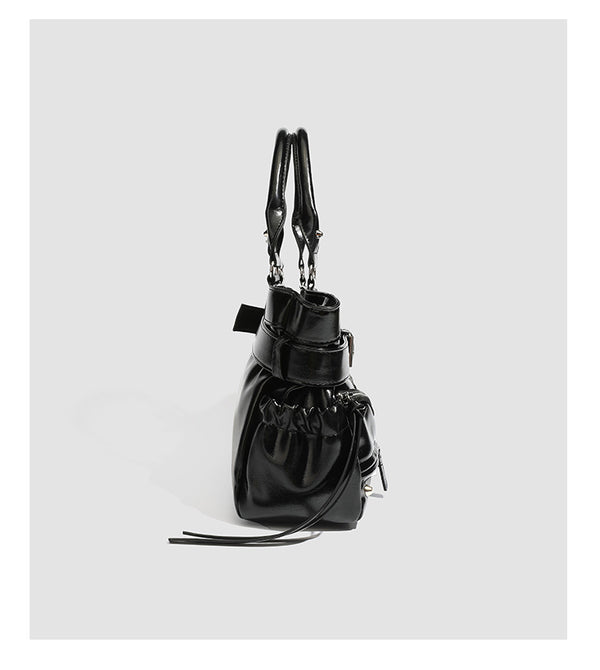 Black glossy structured tote bag with rivet and buckle detail, dual top handles, and detachable shoulder strap, detail view 9
