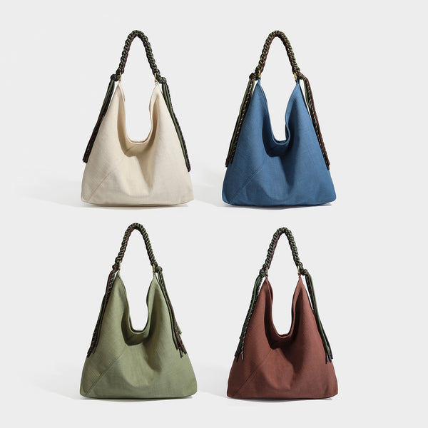 Soft slouchy cream canvas shoulder tote with braided brown and green cord handle, gold-tone ring hardware, and tassel trim