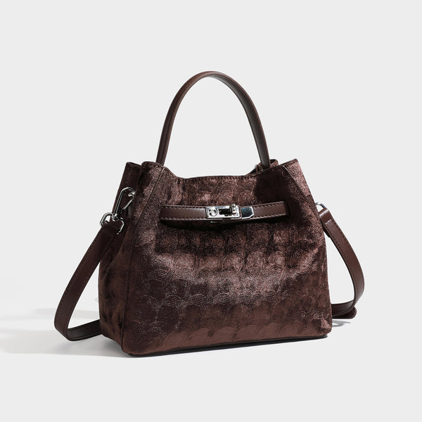 Small structured bucket satchel in embossed velvet-texture fabric with silver turn-lock hardware, rounded top handle, and
