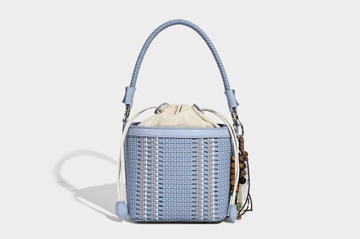 Small woven bucket bag with drawstring top, braided handle, detachable crossbody strap, and silver-tone ring hardware, detail