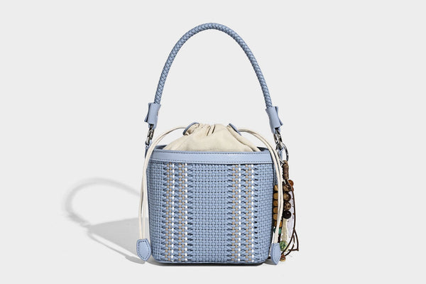 Small woven bucket bag with drawstring top, braided handle, detachable crossbody strap, and silver-tone ring hardware, detail