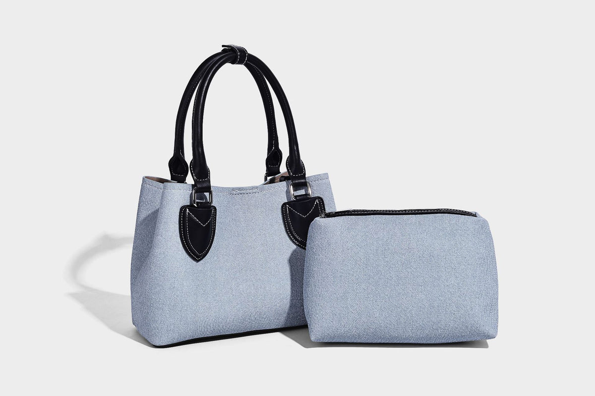 Structured light-blue denim-look tote bag with black leather-look handles, white contrast stitching, silver-tone hardware