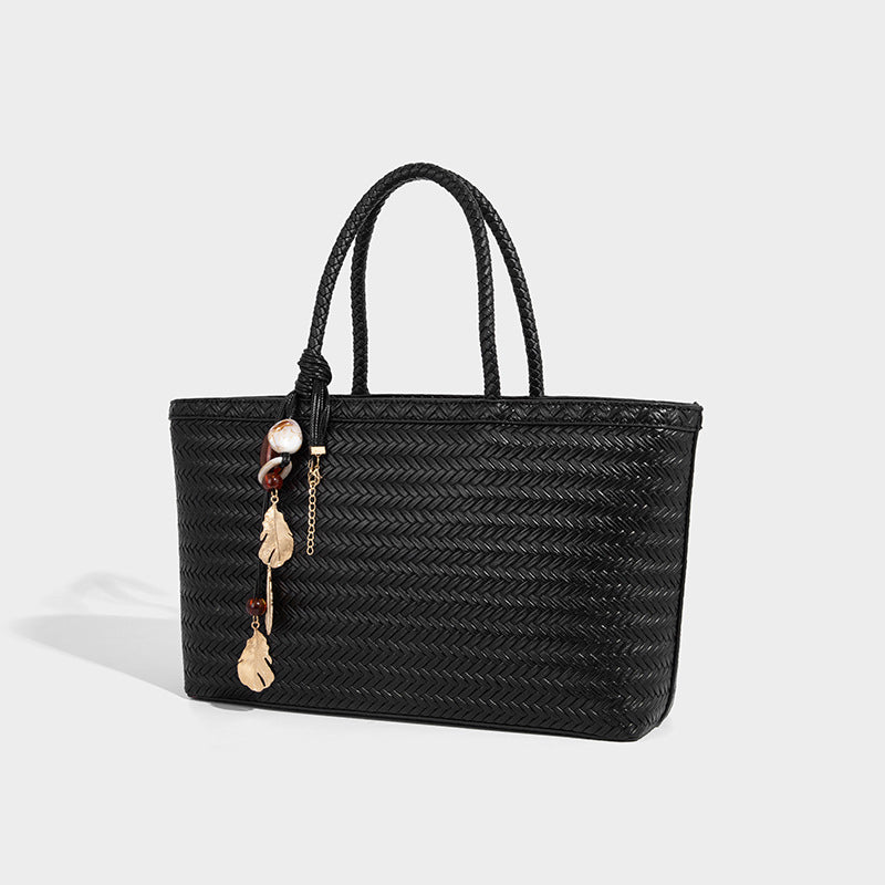 Structured woven-texture tote bag with brown braided top handles, decorative tassel charm, and detachable shoulder strap