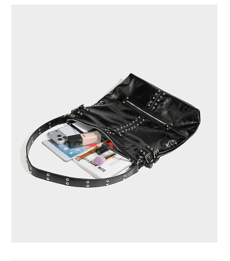 Black glossy leather-look slouchy shoulder bag with silver stud and eyelet hardware, top zip closure, front zip pocket, and