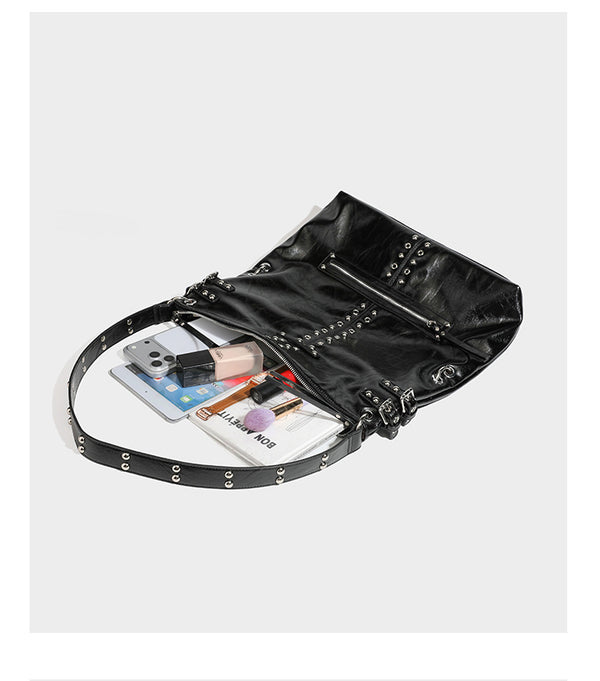 Black glossy leather-look slouchy shoulder bag with silver stud and eyelet hardware, top zip closure, front zip pocket, and