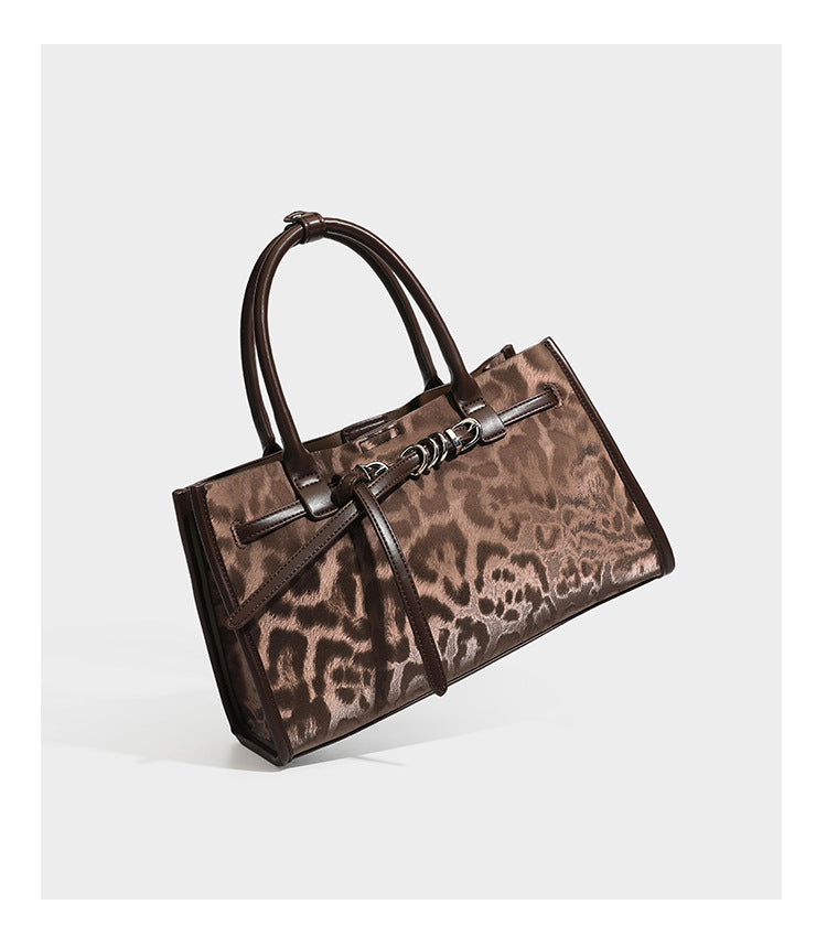 Structured leopard-print tote bag with glossy satin-like finish, dual rounded top handles, silver buckle-and-ring front
