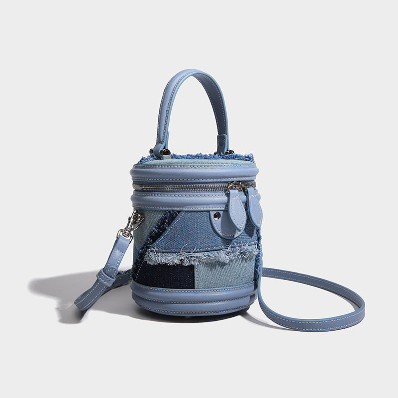 Mini cylindrical barrel bucket bag in denim patchwork with frayed edges, smooth leather-look trim, zip-around top closure