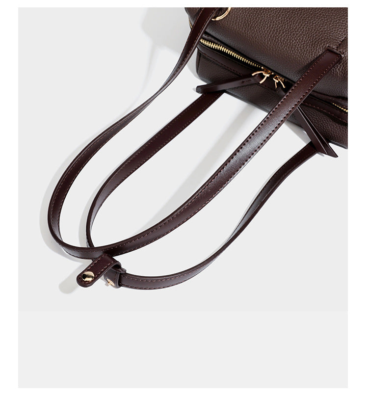 Structured trapezoid shoulder bag in dark brown pebbled leather-look finish with slim double straps, top zip closure, side